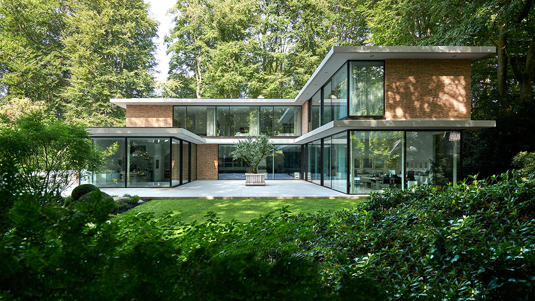 Der Park mit seinem alten Baumbestand bringt die gläserne Villa zur Geltung – und umgekehrt. Bild: Schiebefenster cero von Solarlux.